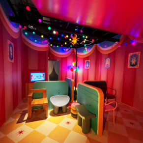 Inside a circus with colour lights, Balloon, interesting weird shaped chairs, and frames in the wall. A mission like playing a musical chair
